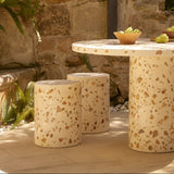 Outdoor setting with a stone table and stools in a garden.