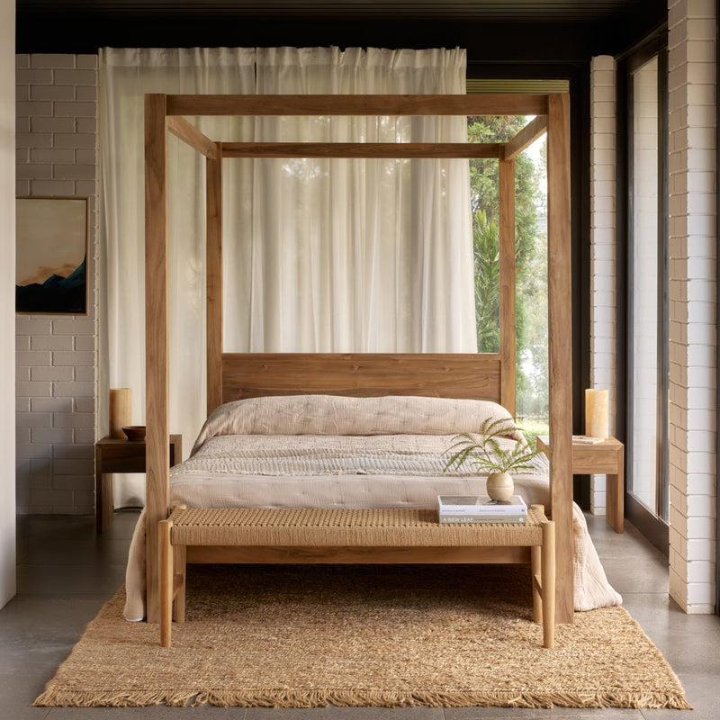 Wooden canopy bed in a modern bedroom with large windows and neutral decor.