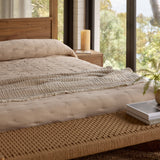 Bedroom with wooden bed, candles, and a view of trees and water.