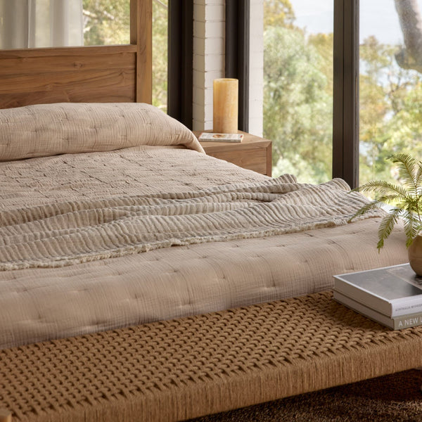 Bedroom with wooden bed, candles, and a view of trees and water.